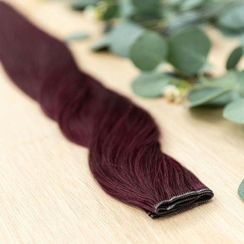 GARNET HIBER WEFT Garnet Hiber Weft is a 22" weft is a vibriant toned level 5 red violet. These wefts offer customization options, including custom sizing, cut, and a seamless fine root base without a return edge. The Hiber Wefts are 22" in length and 32"