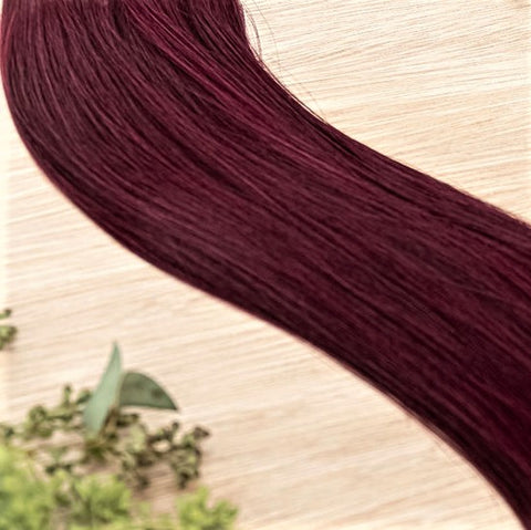 GARNET NATURAL TAPE Garnet weft is a 22" weft featuring vibriant level 5 red violet. Our natural tape hair extensions are carefully crafted to ensure a natural appearance and seamless blending. The hair is placed on the outside of the tape, allowing it to